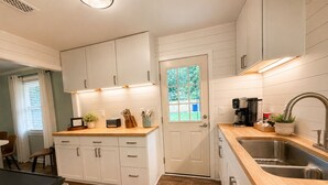 A kitchen with white cabinets, a wooden countertop, a sink, and a door with a window.