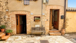 A stone building with numbered doors, a bench, and potted plants.