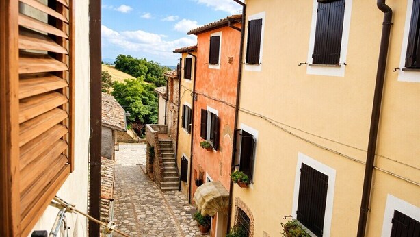 Un vicolo stretto fiancheggiato da edifici, con un percorso in pietra e una scala che conduce a un livello più alto.