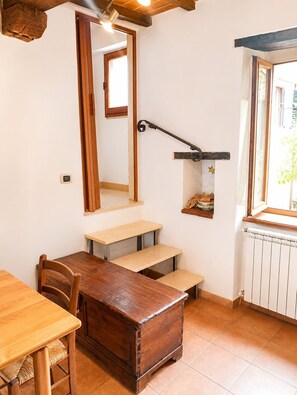 A cozy room with a wooden dining table, a built-in bench, a small staircase, a mirror, and a window with a view. - Dimora del Lago Tiberino e della Foresta Fossile (Dunarobba)