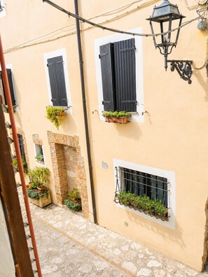 A narrow street with buildings featuring windows with shutters and hanging flower baskets. - Dimora del Lago Tiberino e della Foresta Fossile (Dunarobba)