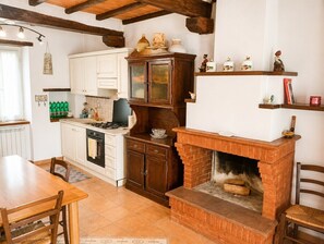 A kitchen with a fireplace, wooden cabinets, and a dining area. - Dimora del Lago Tiberino e della Foresta Fossile (Dunarobba)