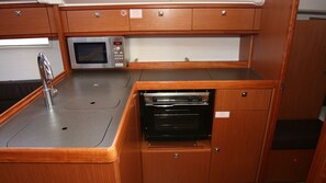 Eine kleine Küchenzeile mit Mikrowelle, Spüle und Backofen.