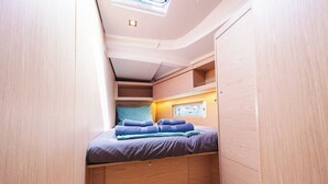 Um alojamento pequeno com uma cama, janela e espaço de armazenamento embutido.