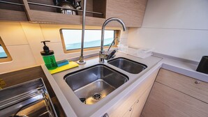Uma cozinha compacta com pia dupla, eletrodomésticos de aço inoxidável e vista pela janela.