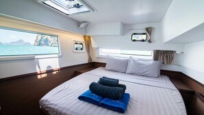 Eine Hütte mit einem Bett, einem Fenster mit Meerblick und einem kleinen Fenster mit Vorhängen.