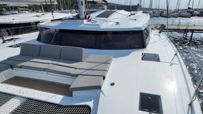 A boat deck with a seating area, a control station, and a view of other boats in the marina. - Sun-Kissed Sailing Adventure in Zadar, Croatia (Biograd na moru)