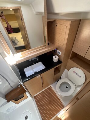 Un baño pequeño y funcional con lavamanos, inodoro y ducha.