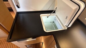 A compact kitchen with a black countertop, a built-in sink, and a white backsplash. - Sun-Kissed Sailing Adventure in Northern Croatia (Punat)