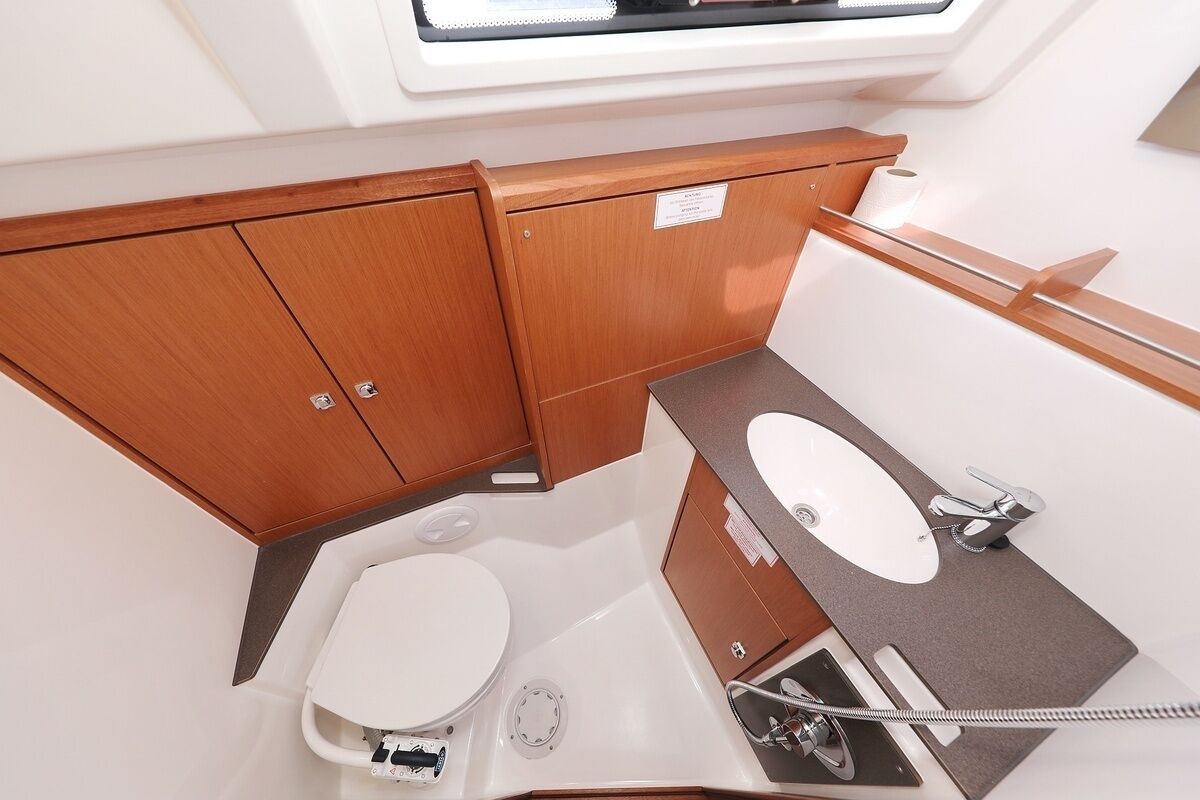 Ein kleines Badezimmer mit Toilette, Waschbecken und Duschbereich, ausgestattet mit Holzschränken und einem Dachfenster.