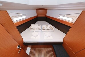 Uma cabine compacta com uma cama de solteiro, duas janelas e um pequeno espaço de armazenamento.