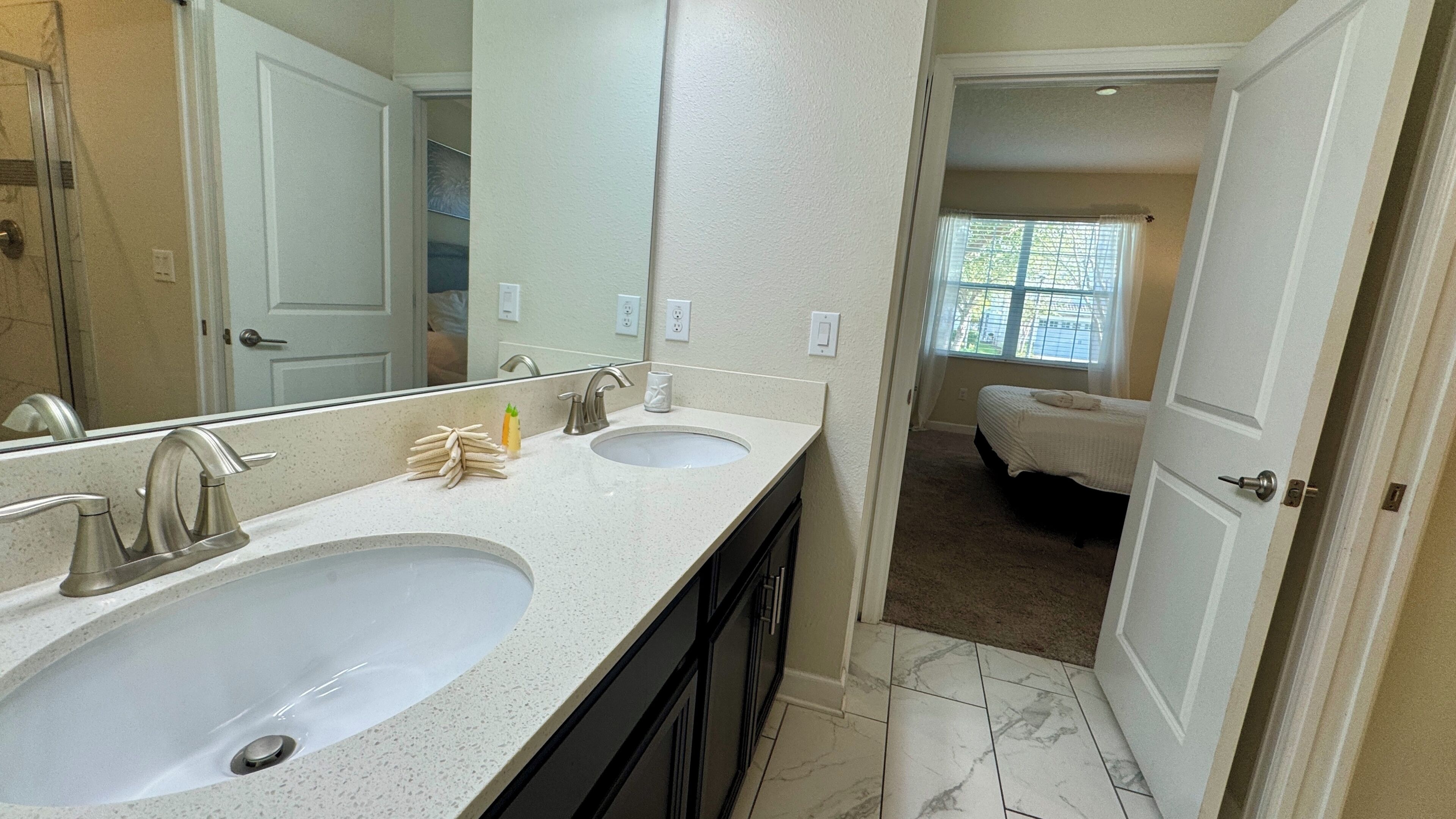 A bathroom with two sinks, a mirror, and a shower.
