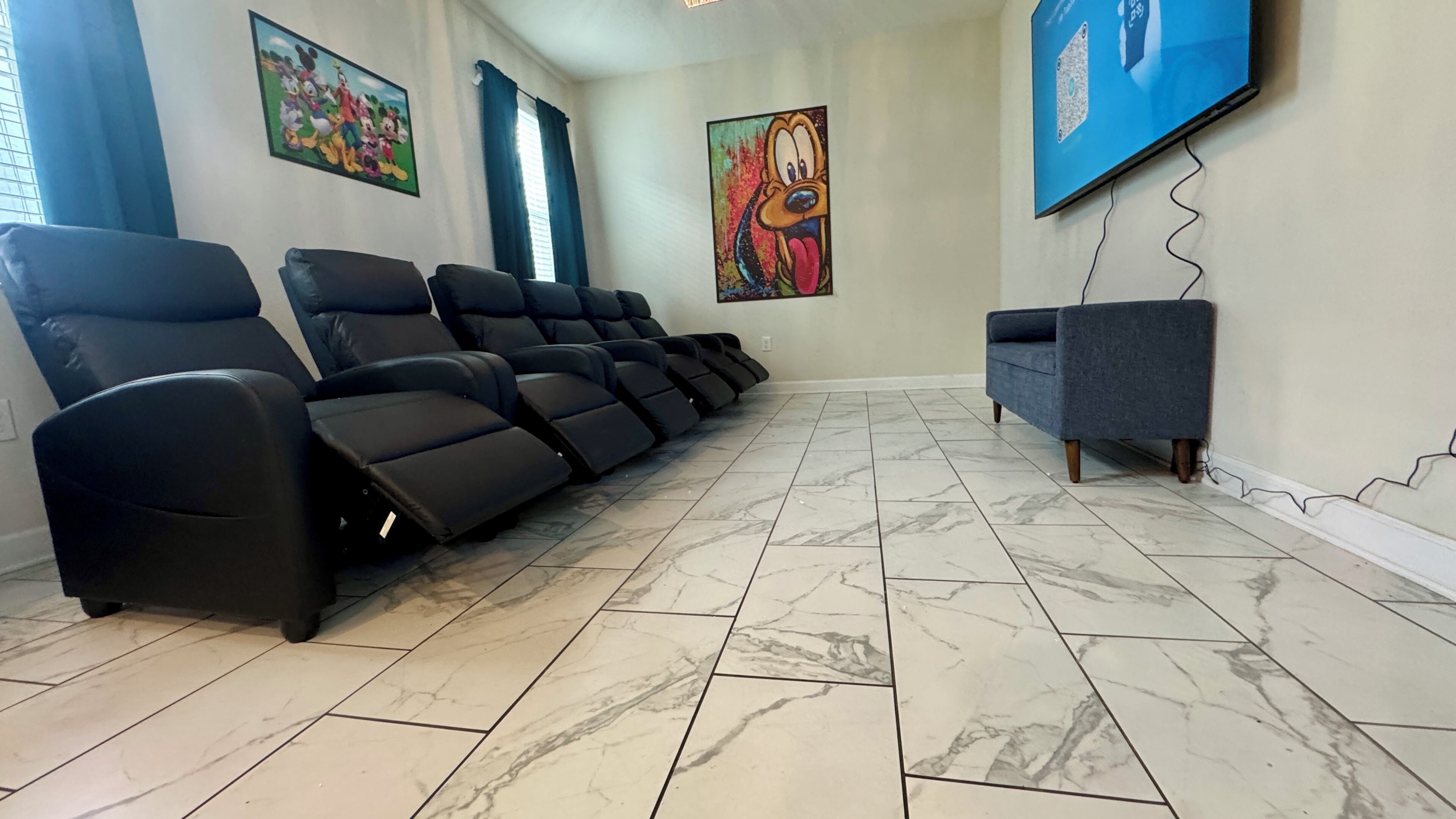 Ein Zimmer mit Massagesesseln, einem Fernseher und Kunstwerken an den Wänden.