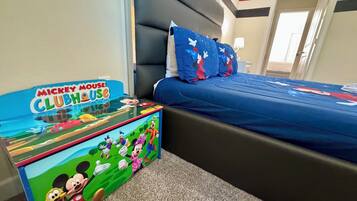 A hotel room with a Mickey Mouse Clubhouse themed table, a bed with blue bedding, and a nightstand.