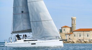 A sailboat with a crew, sailing near a historic building with a tower. - Sun-Kissed Sailing Adventure in Zadar, Croatia (Biograd na moru)