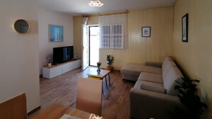 Ett vardagsrum med en soffa, en tv och ett litet bord med en växt.
