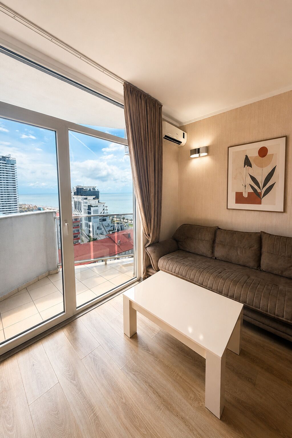 Ein modernes Wohnzimmer mit einer Couch, einem Couchtisch, einem großen Fenster und einem Gemälde an der Wand.