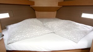 A bed with a patterned blanket and a white pillow in a cabin-style room with wooden walls and a slanted ceiling. - Sun-Kissed Sailing Adventure in Istria, Croatia (Pula)