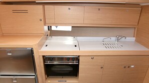 A compact kitchen with a built-in oven, a stainless steel sink, and wooden cabinetry. - Sun-Kissed Sailing Adventure in Istria, Croatia (Pula)
