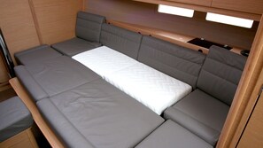 Ein kleines Bett mit einer Matratze und grauen gepolsterten Kopfteil und Fußteil.