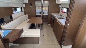 Interior compacto de una caravana con cocina americana, zona de comedor y litera.