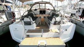 A boat deck with a steering wheel, a small table, and a seating area. - Sun-Kissed Sailing Adventure in Istria, Croatia (Pula)