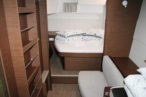 Habitació petita amb llit, una banca i prestatges de fusta integrats.