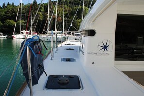 A yacht with 'NAVIGARE YACHTING' branding, a cabin with a window, and a view of other yachts docked at a marina. - Dubrovnik Delight: A Sun-Kissed Sailing Experience (Komolac)