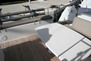Convés de barco com assentos, painel de controle e guarda-corpo.