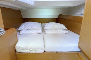 Habitació compacta amb un llit individual, capçalera de fusta i matalàs blanc.