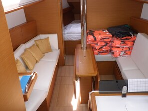 A compact cabin with a sofa, a small table, and a bed. - Sun-Kissed Sailing Adventure in Zadar, Croatia (Bibinje)