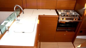 A compact kitchen with a stainless steel stove, a sink, and wooden cabinetry. - Sun-Kissed Sailing Adventure in Northern Croatia (Punat)