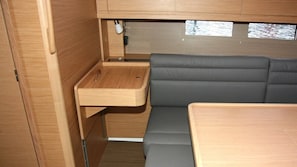 Ein kompaktes Wohnmobil-Interieur mit Holzschränken, einem kleinen Tisch und einer gepolsterten Sitzecke.