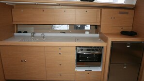 Eine kleine Küche mit Holzausstattung, einem Edelstahlspülbecken, einem Backofen und einem Kühlschrank.