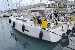 En segelbåt med namnet ”PUFOUR 430” låg förtöjd i en småbåtshamn tillsammans med andra båtar.