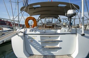 A boat's bow with a lifebuoy, a nameplate, and a mast.