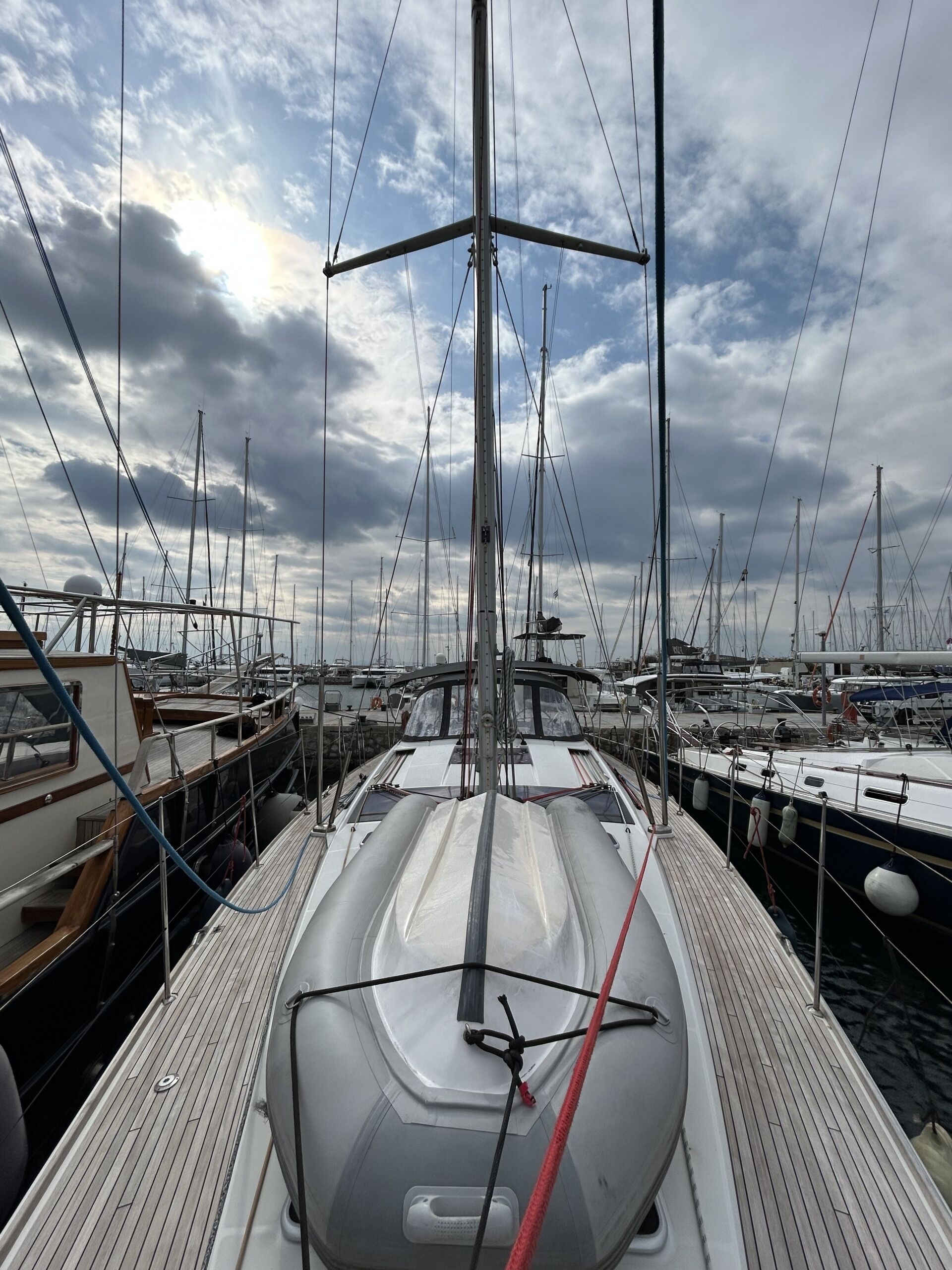 Marina con varios veleros amarrados, destacando una cubierta de madera y cielo despejado.