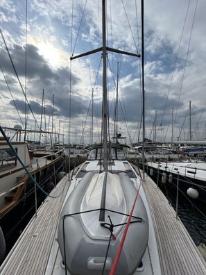 Marina con varios veleros amarrados, destacando una cubierta de madera y cielo despejado.