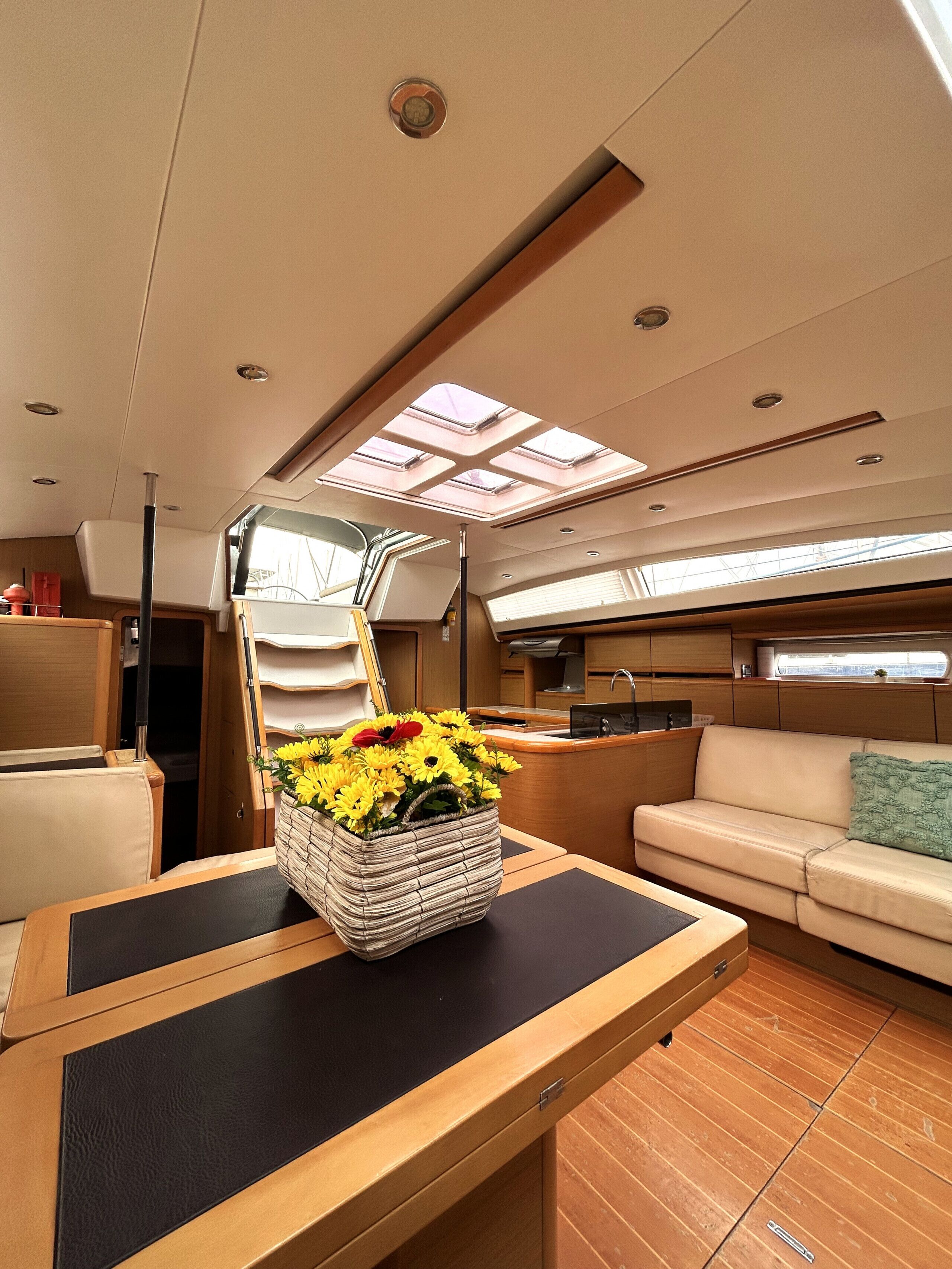 A yacht interior with a dining area, a sofa, a kitchen, and a skylight.