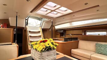 A yacht interior with a dining area, a sofa, a kitchen, and a skylight.
