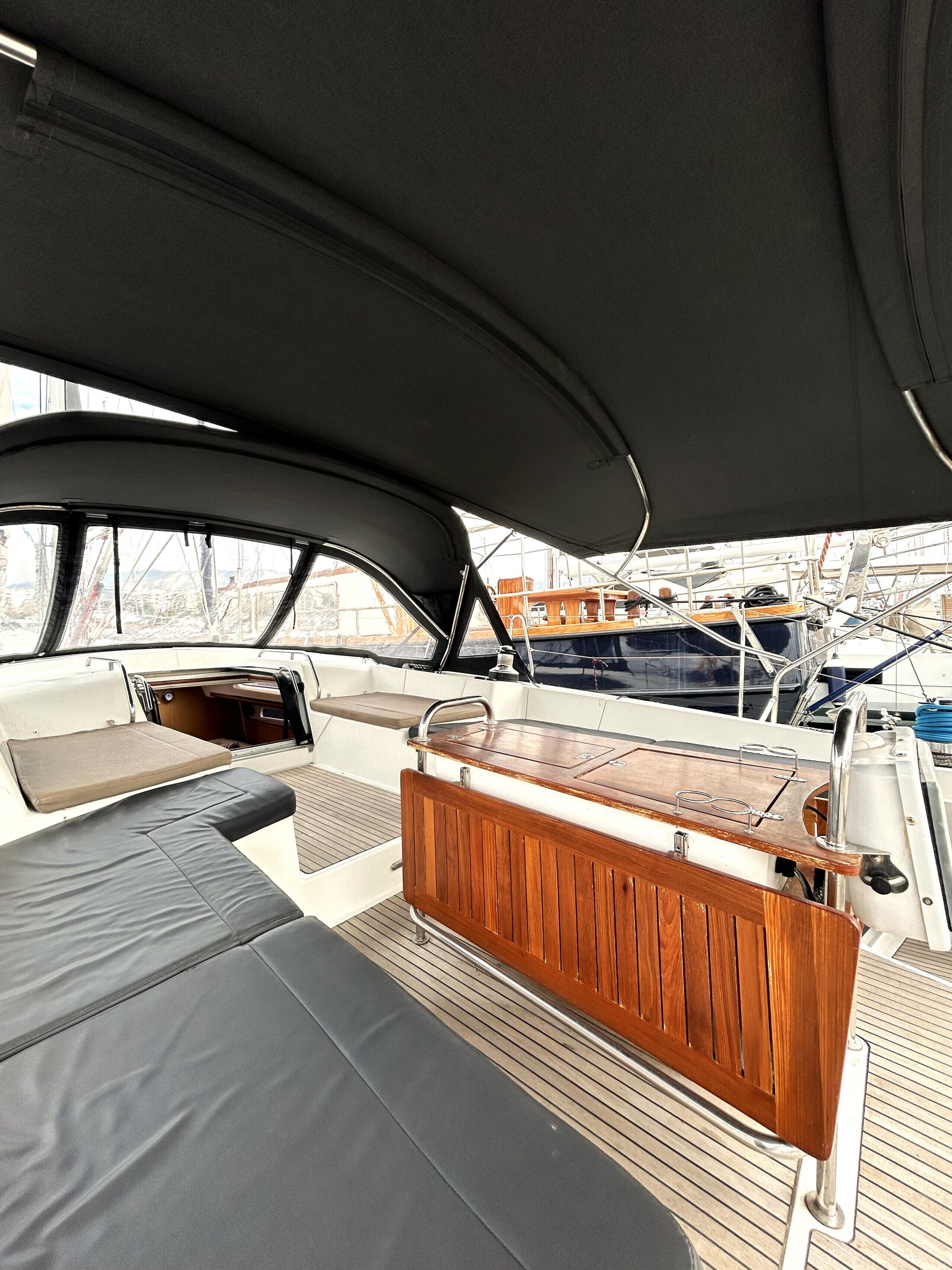 L’intérieur d’un bateau, avec un espace salon doté de sièges rembourrés, un pont en bois et une vue sur les autres bateaux.