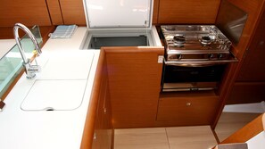 A compact kitchen with a stainless steel stove, a sink, and wooden cabinets. - Sun-Kissed Sailing Adventure in Istria, Croatia (Pula)