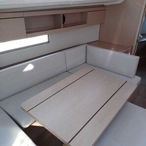 Ein kompakter, moderner Wohnraum für ein Wohnmobil mit integriertem Tisch und Sitzgruppe.