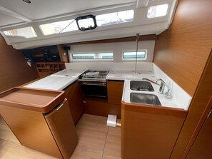 A compact galley kitchen with a stove, sink, and storage cabinets. - Sun-Kissed Sailing Adventure in Islas Baleares, Mallorca (Palma)