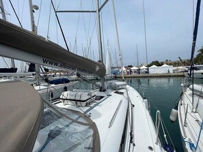 A marina with multiple sailboats docked, a website banner, and a clear sky. - Sun-Kissed Sailing Adventure in Islas Baleares, Mallorca (Palma)