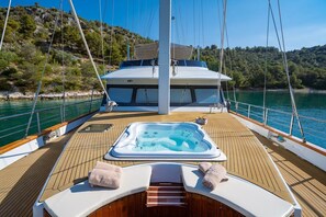 Ein Yachttdeck mit Whirlpool, Liegestühlen und einem überdachten Bereich.