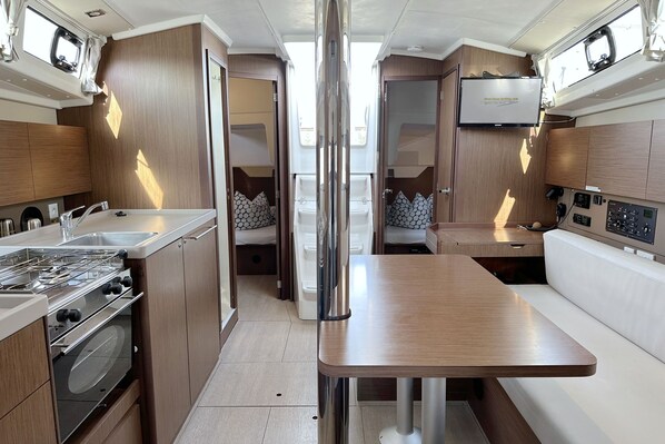 A compact kitchen with a stove, sink, and a small dining area. - Sun-Kissed Sailing Adventure in Istria, Croatia (Pula)