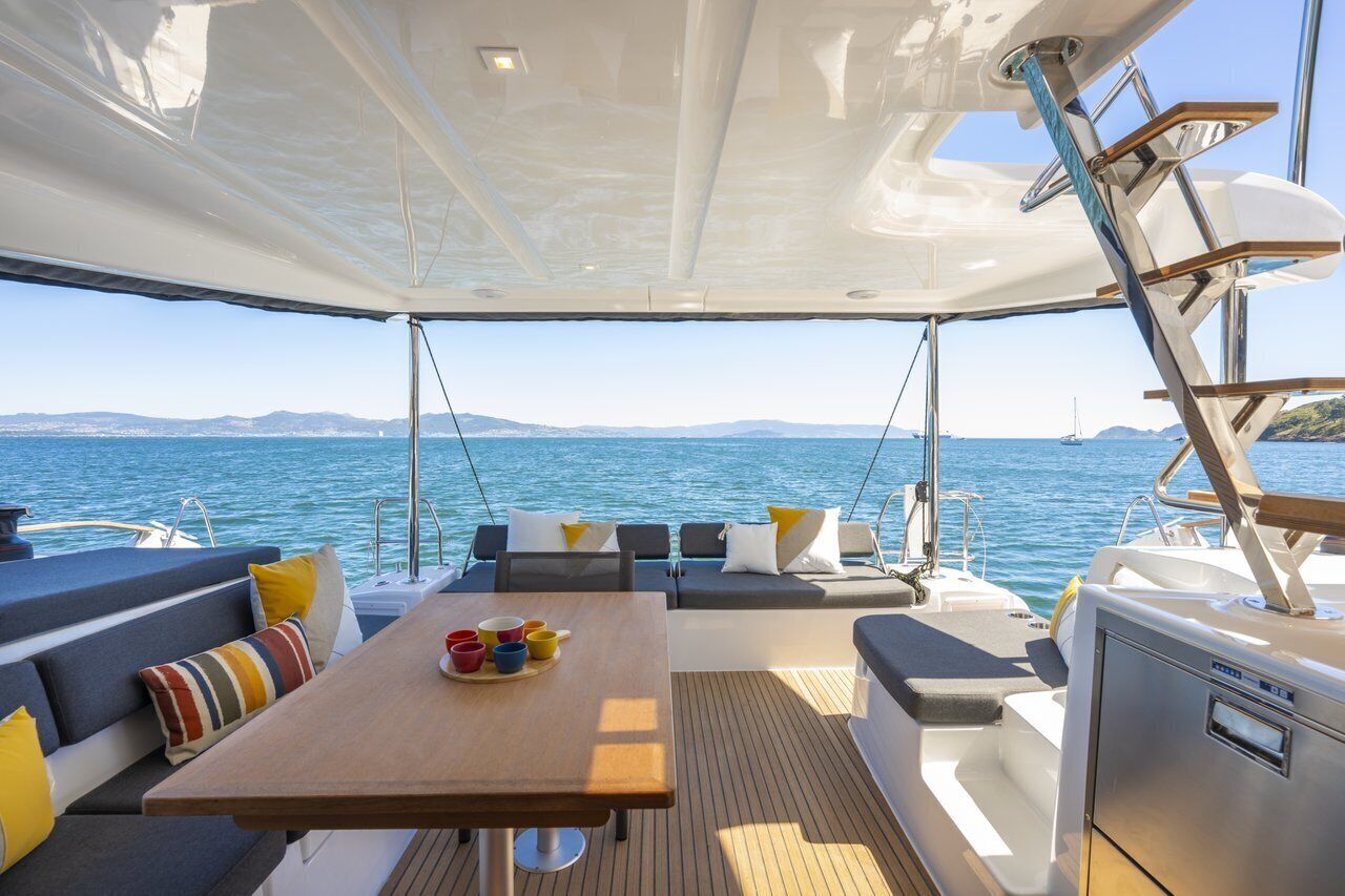 A yacht deck with a table, seating, and a view of the sea.