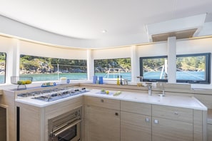 A modern kitchen with a large island, built-in oven, and a view of the sea. - Phuket Sun and Beach Sailing Extravaganza (Pa Klok)