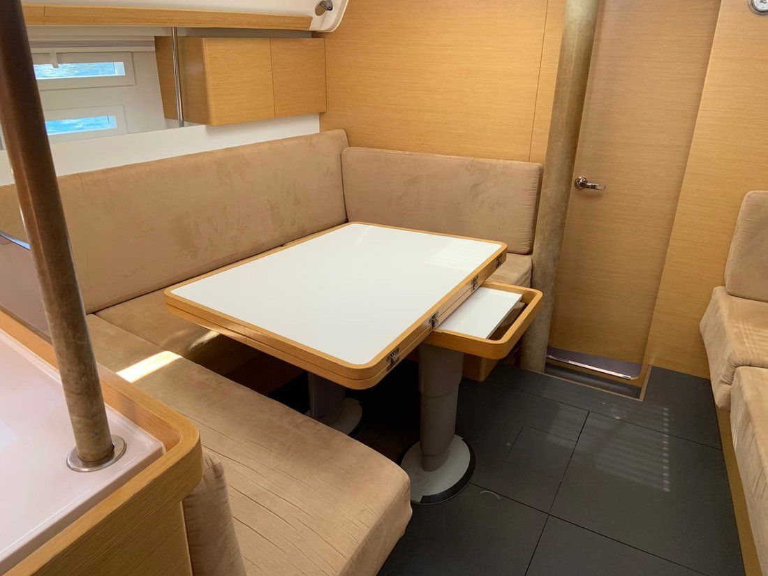 A compact, well-lit interior with a central table, cushioned seating, and a door.